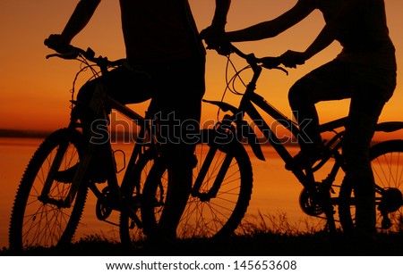 silhouettes of couples in love ride bicycles along the beach  No faces