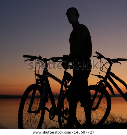 silhouettes of couples in love ride bicycles along the beach with reflection on water No faces