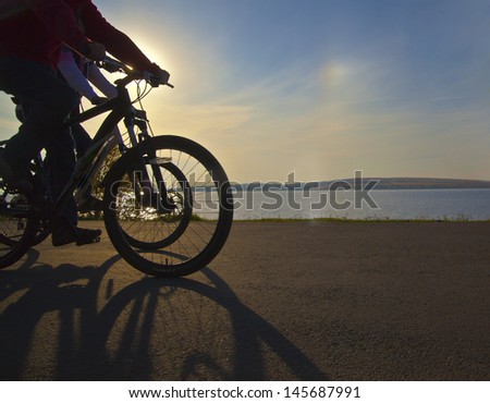 Image of sporty couple on bicycles outdoors against sun and sunset. Silhouette with shadows No faces