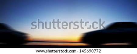 blurry silhouette of two cars drive on the way to meet each other on sunset background Copy space for inscription