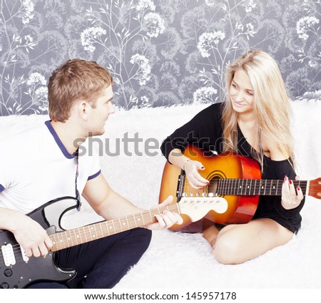 guitarists of a rock band with a guitar in home interior on black wall background