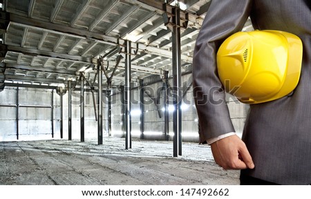 engineer yellow helmet for workers security against the support beams of the unfinished industrial workshop or room inside   Copy space for inscription
