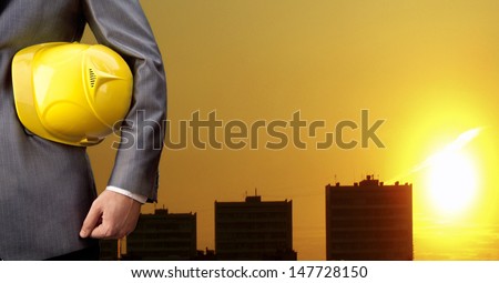 engineer yellow helmet for workers security over sun set sky and three houses Construction man holding hardhat