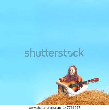 Country redhead curly girl playing guitar at haystack Copy space for inscription