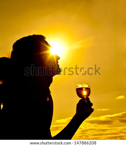 silhouette of a young man in the background of the yellow sky with a glass of white wine Copy space for inscription