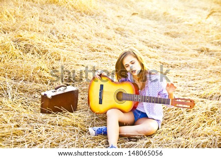 Copy space for inscription Horizontal Country latin hispanic brunette girl playing guitar at haystack