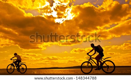 silhouettes of mother and child on bicycle against sunset sky Copy space for inscription