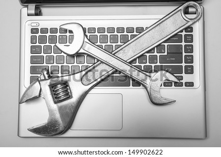 gray laptop with a vanadium spanner on the keyboard Two metal tools on the computer symbol repair, software installation, upgrade, improvement