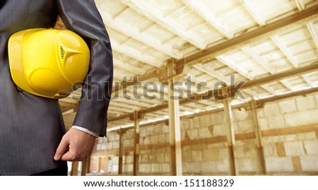 engineer yellow helmet for workers security on background empty brown warenhouse with metal pillars of  Copy Space for inscription