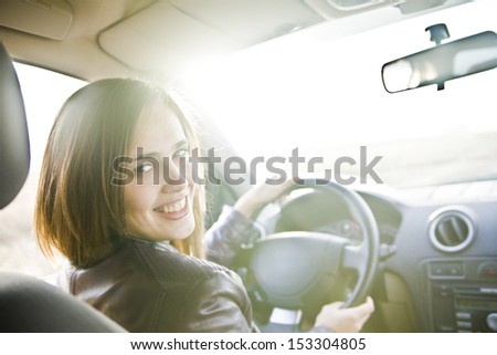 Portrait of beautiful young latin hispanic brunette woman in the new car - indoor keeps the wheel turning around and smiling and looking at the passengers in back seat. The idea of  taxi driver
