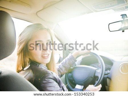 Portrait of beautiful young latin hispanic brunette woman in the new car - indoor keeps the wheel turning around and smiling and looking at the passengers in the back seat. The idea of  taxi driver