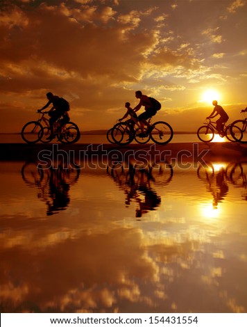 Image of sporty company six friends on bicycles outdoors against sunset. Silhouette A lot phases of motion of a single cyclist along the shoreline coast Reflection on water Space for inscription
