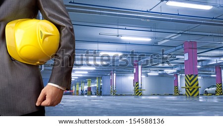 engineer yellow helmet for workers security against the background of underground parking for cars with the prospect Copy space for inscription