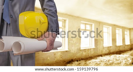 engineer yellow helmet for workers security with construction plans  on the background of a old apartment buildings of gray