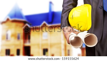 engineer yellow helmet for workers security on the background of a new rise  brick apartment buildings with blue roof