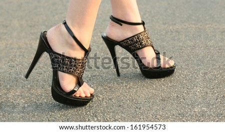 Sexy female high heeled black shoes on the asphalt way