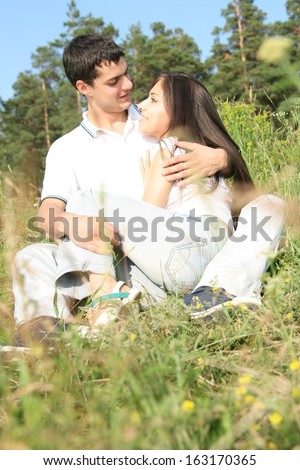 Young latin hispanic couple in white shirt playing and embracing around in the nature - blue sky and forest background Girl looking at camera  Copy space for inscription