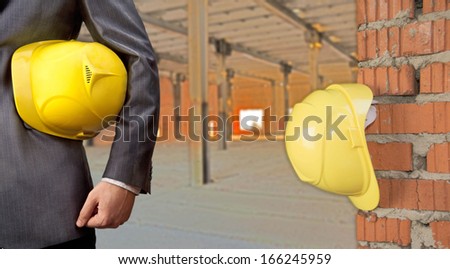 adult engineer or inspector hand holding yellow plastic helmet for workers security over empty space warehouse or home interior  background No face Copy space for inscription