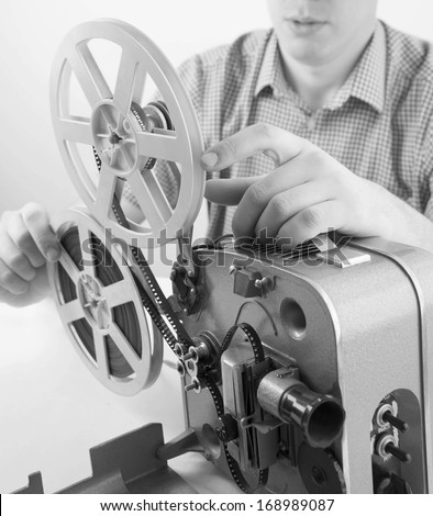 Man hand holding object ( cinema projector old-fashioned ) on white table .Focus on finger
