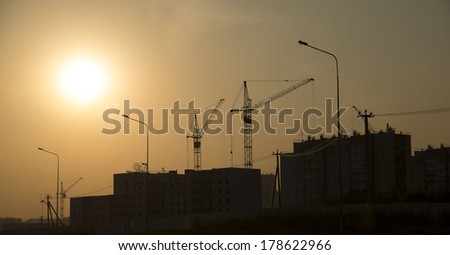 Background of Construction site with home asphalt way latern construction cranes on yellow sun set cloudy sky with rays light  backdrop