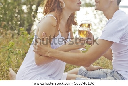 Young adult happy sexy couple embracing and celebrating with champagne at picnic on green summer trees background No face