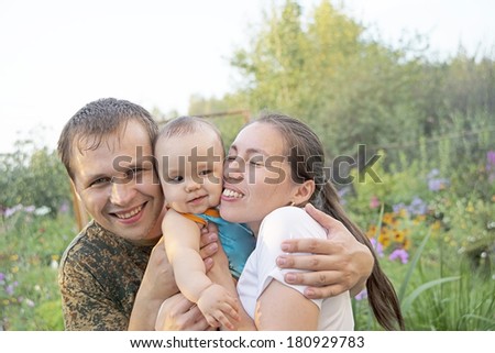Portrait of Young adult and happy family get stroll on the green summer garden and sky background Baby between parents