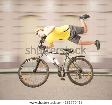 Potrait of young adult man on the mountain  bicycle in leather gloves yellow shirts gray shorts orange cap snickers and sunglasses wall doors background Male going along old retro building on cycle
