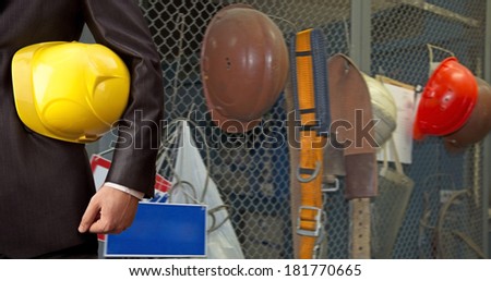 torso adult engineer or inspector hand holding yellow plastic helmet for workers security over empty space warehouse or industrial interior background No face Copy space for inscription