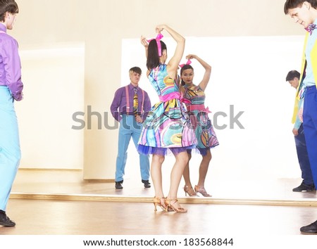 Portrait of three Happy teenage retro rock band on in very colorful dress on mirror reflection on wall background Two man and one woman full length looking at camera