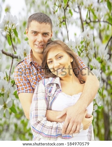 Portrait of latin hispanic brunette couple woman with boyfriend man in spring flower apple trees garden background