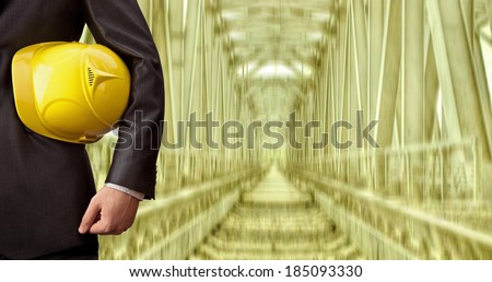 torso engineer hand holding yellow helmet for workers security against background of an underground metal bridge mine with arc legs and rails for trolleys with coal
