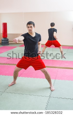 Portrait of young adult latin hispanic man boxer training in gym boxing punching bag Aggressive asian male inside wall room against window background Reflection on mirror
