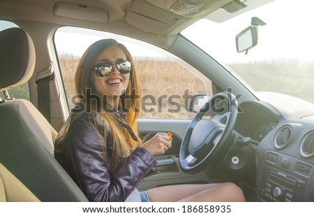 Portrait of beautiful young latin hispanic brunette woman in  new car  indoor and smiling and looking at  passengers in back seat. The idea of taxi driver Cute girl in sunglasses with candy