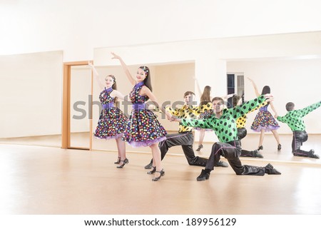 Portrait of four Happy young adult retro dance band on in very colorful dress on mirror reflection on wall background Two man and woman full length looking at camera Copy space for inscription