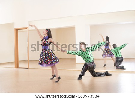 Portrait of two Happy teenage retro dance band on in very colorful dress on mirror reflection on wall background Couple man and one woman full length looking at each other Dirty dancing