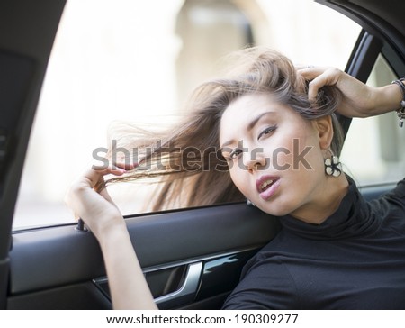 portrait of beautiful cute asian woman with windy hair sitting inside a new modern car looking far away on auto window background Beautiful girl in windy weather day Hand touch smiley face near lips
