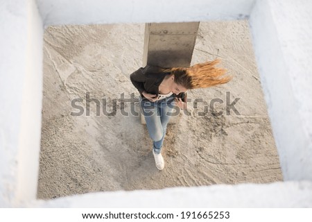 Portrait of sexy girl dreaming and posing of concrete roof background sun set light on long hair  Fashion woman in black leather jacket looking down on floor