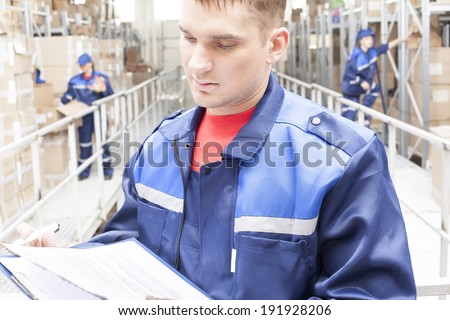 warehouse three workers one man and two woman in a special blue uniform is recording and accounting of contents in cardboard boxes in stock No faces idea account statistics rediscount cargo arrival