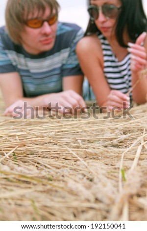 Focus on dry yellow autumn grass Happy couple in love is lying on hay background De focused pair faces with sunglasses Copy space for inscription