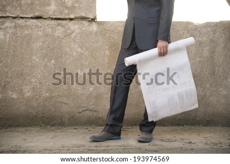 Well dressed Engineer\'s Hand  in dark suit holding blueprint paper plan  on gray concrete wall background No face Unrecognizable person