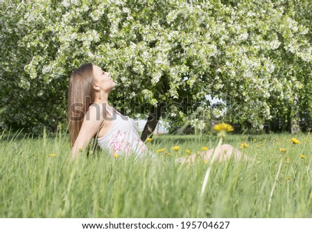 Full length portrait of beautiful young woman lying on a meadow against white flower on apple tree Cute slim girl with long brown hair in gray dress looking up and enjoying Copy space for inscription