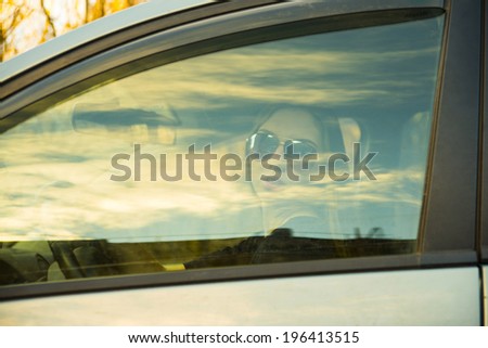 Portrait of Woman in sunglasses and leather gloves looking through the car side window glass with long brown hair on autumn park background