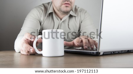 No face Unrecognizable person of business man using gray silver laptop with a white cup of coffee Businessman working on wooden natural table