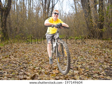 Full length portrait of Young attractive sport man standing on fall leaves  in the autumn park Male based on modern  bicycle on yellow park background