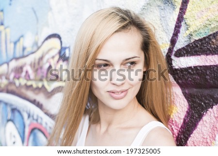 Close up portrait of Redhead young adult girl with smiley face looking far away on colorful graffiti art wall background in perspective Latin hispanic woman with long hair dreaming about something