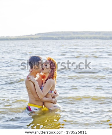 Portrait of Couple having fun in sea Man and Woman embracing and kissing in summer warm water with wave on sky background