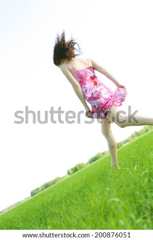 Back view Running girl in red sexy short red dress run on fresh spring green grass field  sunlight on summer sky background Copy space for inscription
