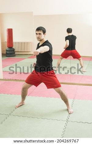Reflection on mirror Copy space for inscription Portrait latin hispanic man boxer training in gym boxing punching bag Aggressive asian male inside wall room against window background Vertical format