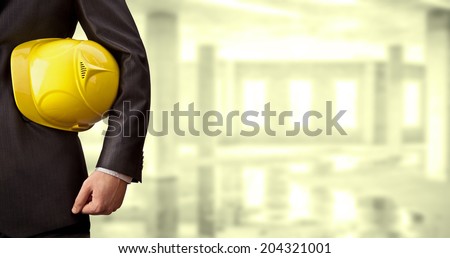 torso engineer or worker holding in hand yellow helmet for workers security over empty old building inside concrete house background Copy Space for inscription
