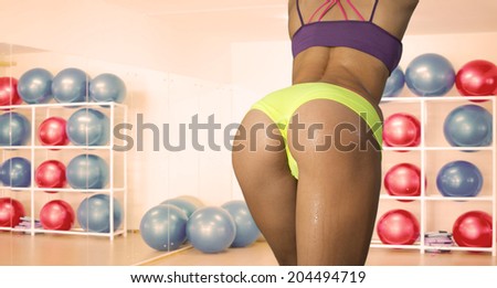 woman back with buttocks, slim waistline sexy style shorts over underwear Water drops on elastic brown wet skin No face  Copy space for inscription On wall shelf in gym with rubber ball background